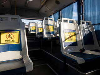 No sitting sign on bus seat. No people on bus. empty seat. flare light from window.