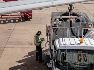 a male staff writing bill of fuel used of the aircraft. Aircraft engineer working on refueling.