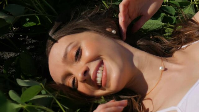 Woman lies in the green grass on the field. Beautiful model lying on the grass.