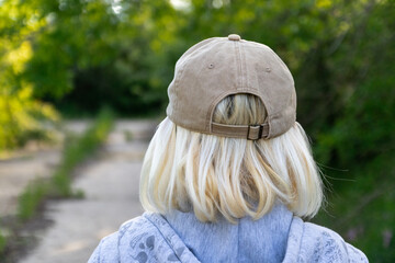 View from the back of blonde woman in a baseball cap on the street