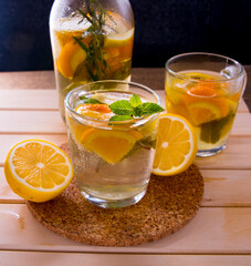 Still life, a bottle and two glasses with a drink, with mint lemon, orange on the table