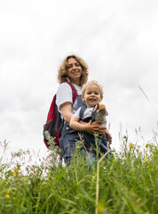 Fototapeta premium mom and her son walk in the park in identical denim jumpsuits. they enjoy time together and love each other. High quality photo