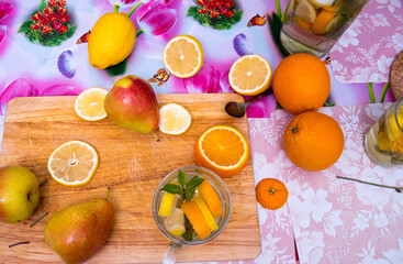 Two glasses and a bottle with drinks from fruits, fruits pear, pelesin, lemon lie on a cutting board