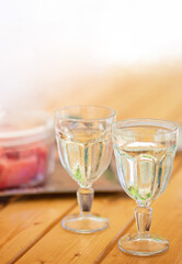 two glass of water pouring into glass on wooden table outdoors
