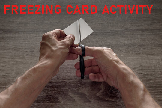 male hands with scissors cut the payment card. concept of liquidation, destruction of deactivation, decommissioning with the inscription freezing card activity.