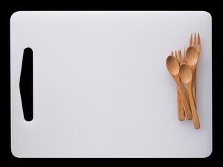 Wooden spoons and forks on background of white chopping board