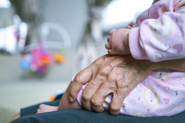 close up of old people hand holding newborn baby 