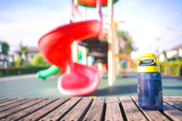 sport bottle of water on the wooden bench at kid playground in the park