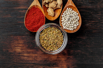 Vivid colorful spices in wooden spoons on wooden background