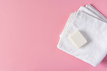 White towel with soap on a pink background, bath spa accessories