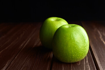 Two green apples on dark rustic woden background. Copy space.