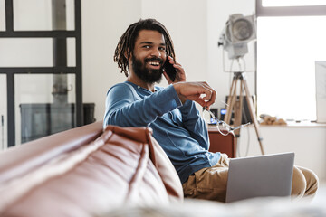 Handsome young african man sitting on a leather couch at home