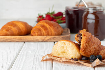 Fresh croissant decorated with berries on white wooden board