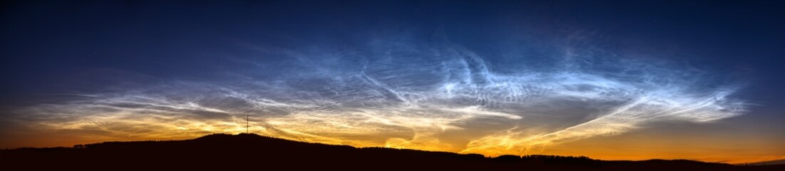 A rare atmospheric phenomenon noctilucent clouds. Night glowing silvery clouds. Ultra wide panorama.