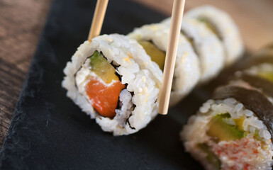 Eating sushi roll set with chopsticks. Japanese food.
