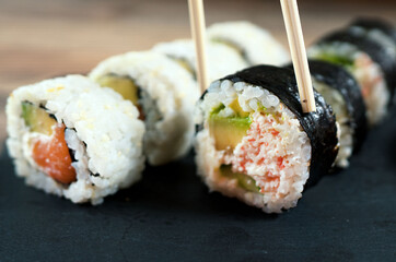 Eating sushi roll set with chopsticks. Japanese food.