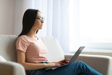 Student Girl Using Laptop Thinking Sitting On Sofa At Home