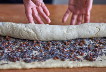 Woman rolls dough with jam for baking.