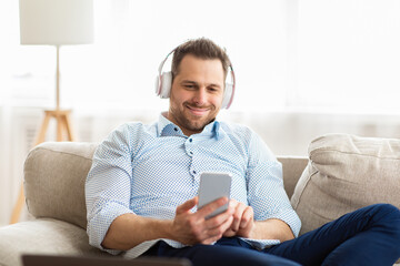 Happy man listening to music sitting on couch