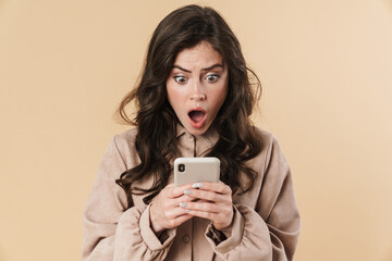 Image of shocked beautiful woman typing on mobile phone