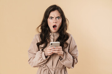 Image of shocked beautiful woman typing on mobile phone