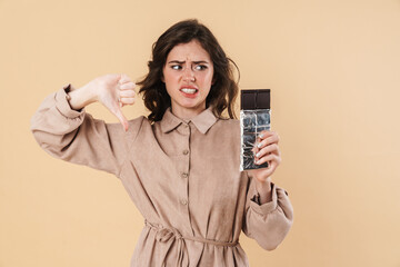 Image of displeased woman showing thumb down and holding chocolate
