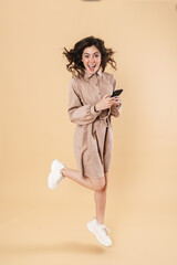Image of excited nice woman jumping while using cellphone
