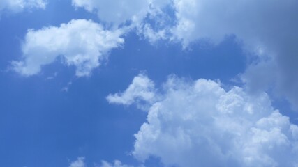 Horizontal shot of beautiful white puffy clouds in a clear blue sky