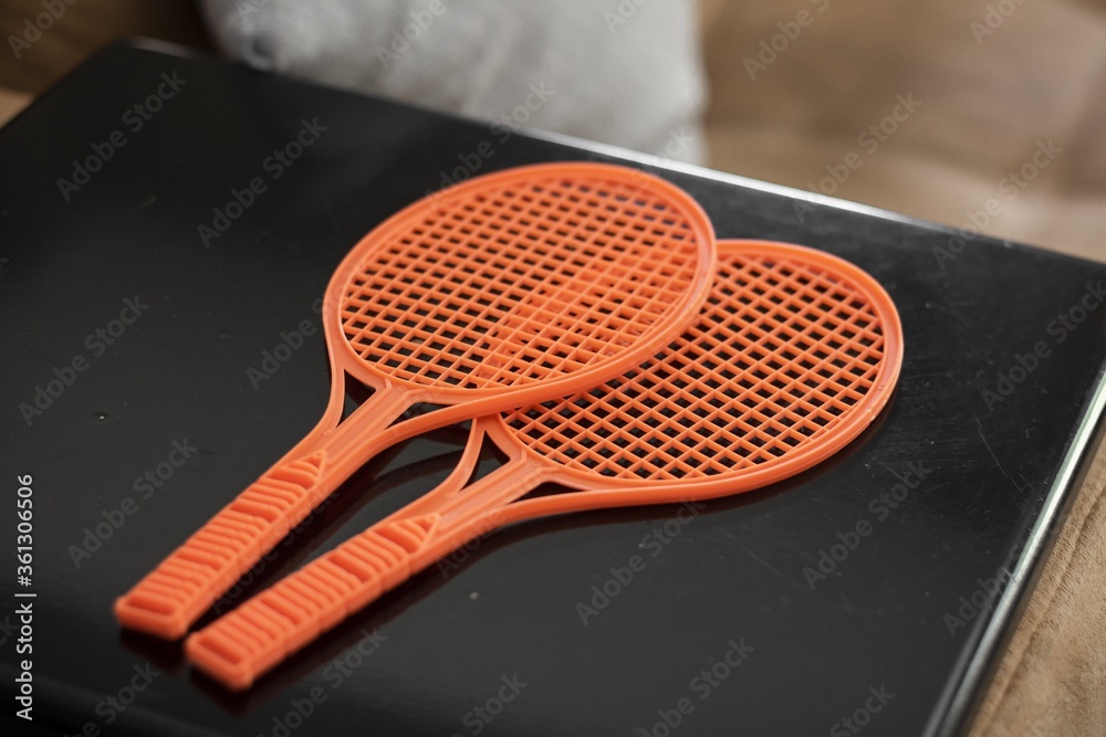 Sticker High angle shot of a pair of orange Tennis rackets on a black laptop