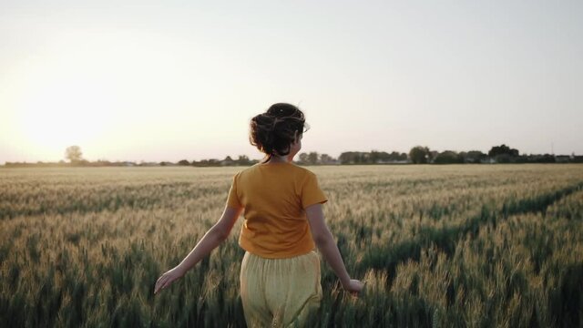 Teenage girl enjoy with sunshine in wheat field.