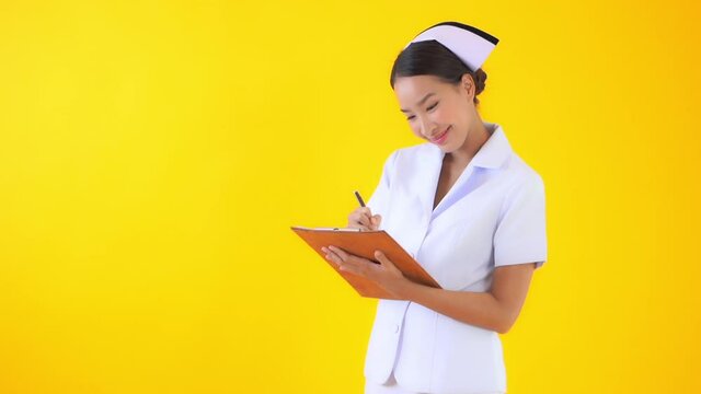 A woman in a traditional nurse's uniform and cap makes eye contact, listens, and writes in the medical chart. Copy space