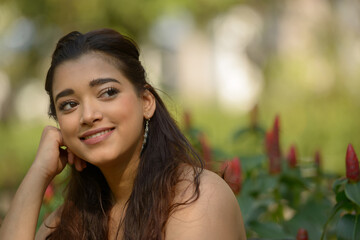 Naklejka premium Face of happy young beautiful Indian woman thinking at the park