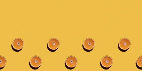 Colorful fruit seamless pattern of halves of oranges on a yellow background. Top view, copy space