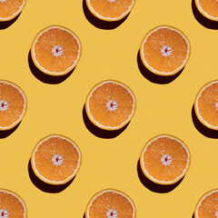 Colorful fruit seamless pattern of halves of oranges on a yellow background. Top view