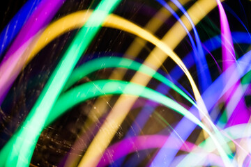 Colorful pattern of green, yellow, blue and pink dynamic lines of light. Modern blurred background. Art concept of lighting effects.