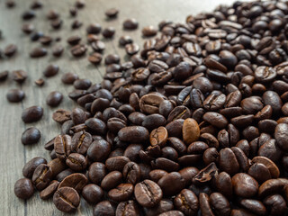 Black coffee in grains on the surface of a wooden table.