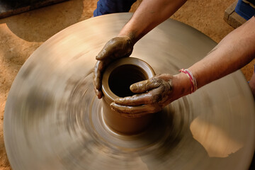 Pottery - skilled wet hands of potter shaping the clay on potter wheel. Pot, vase throwing. Manufacturing traditional handicraft Indian bowl, jar, pot, jug. Shilpagram, Udaipur, Rajasthan, India