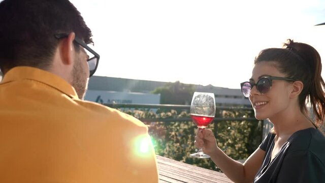 young couple on the terrace of their house celebrating with a glass of wine at sunset