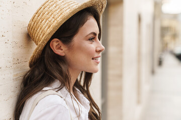 Portrait of nice happy woman in straw hat smiling and looking aside