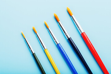 Multi-colored paint Brushes on a blue background.