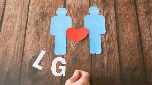 Two people sign with paper heart symbol on wooden background, lgbt concept