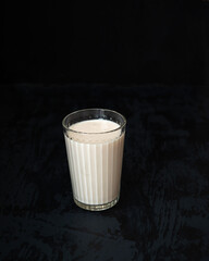 Milk in a glass cup on a black background
