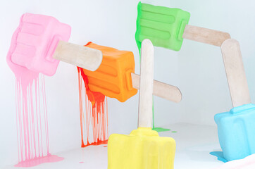 Creative minimal summer background of colorful melting ice cream dummies in white room, bright popsicles on a stick. Light and bright pops of color.