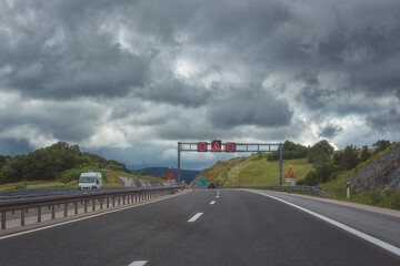 Picturesque highway in Croatia (autocesta A), the main automobile way with pointers and road signs. Scenic daytime landscape with fantastic clouds, shoot in motion