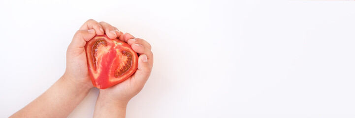 Children hands holding half a tomato.
