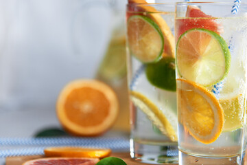 Health care, fitness, healthy nutrition diet concept. Fresh cool homemade citrus infused detox water with grapefruit, orange, lemon and lime and ice in a jug and glasses for spring summer days.