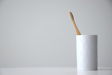 Eco friendly bamboo toothbrush in white holder on white background with free space for text. Dental...