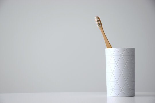 Eco friendly bamboo toothbrush in white holder on white background with free space for text. Dental care and teeth treatment concept. Copy space.