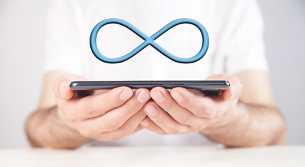 Man holding smartphone with a Infinity symbol.
