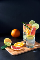 Health care, fitness, healthy nutrition diet concept. Fresh cool homemade citrus infused detox water with grapefruit, orange, lemon and lime and ice in glasses on dark background.